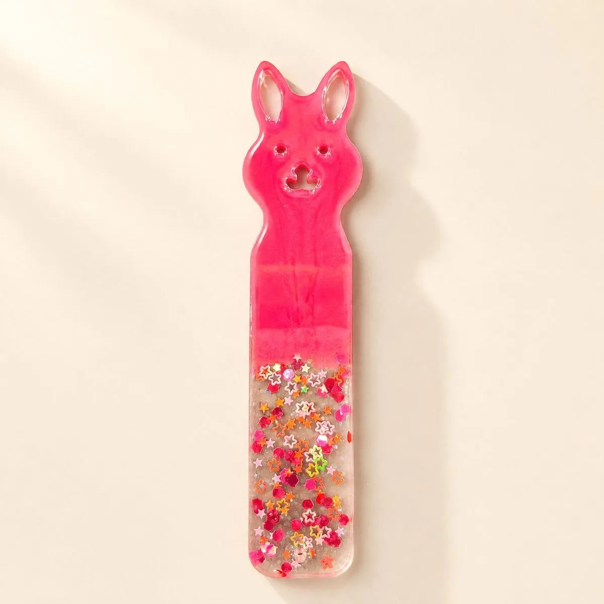 Hot pink bunny bookmark with a carved face and a lower half of star confetti in clear resin