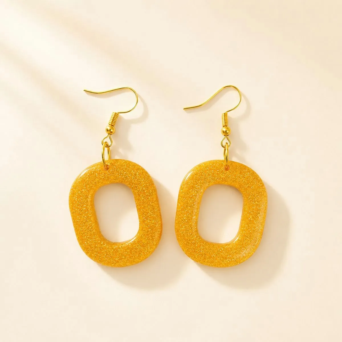 Open rounded-square hoop earrings in dense warm gold glitter resin