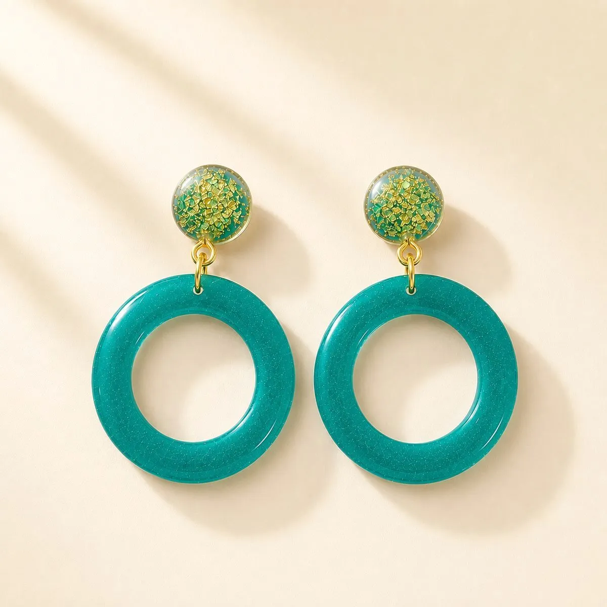 Small speckled stud above a large open teal-blue hoop, with gold fittings