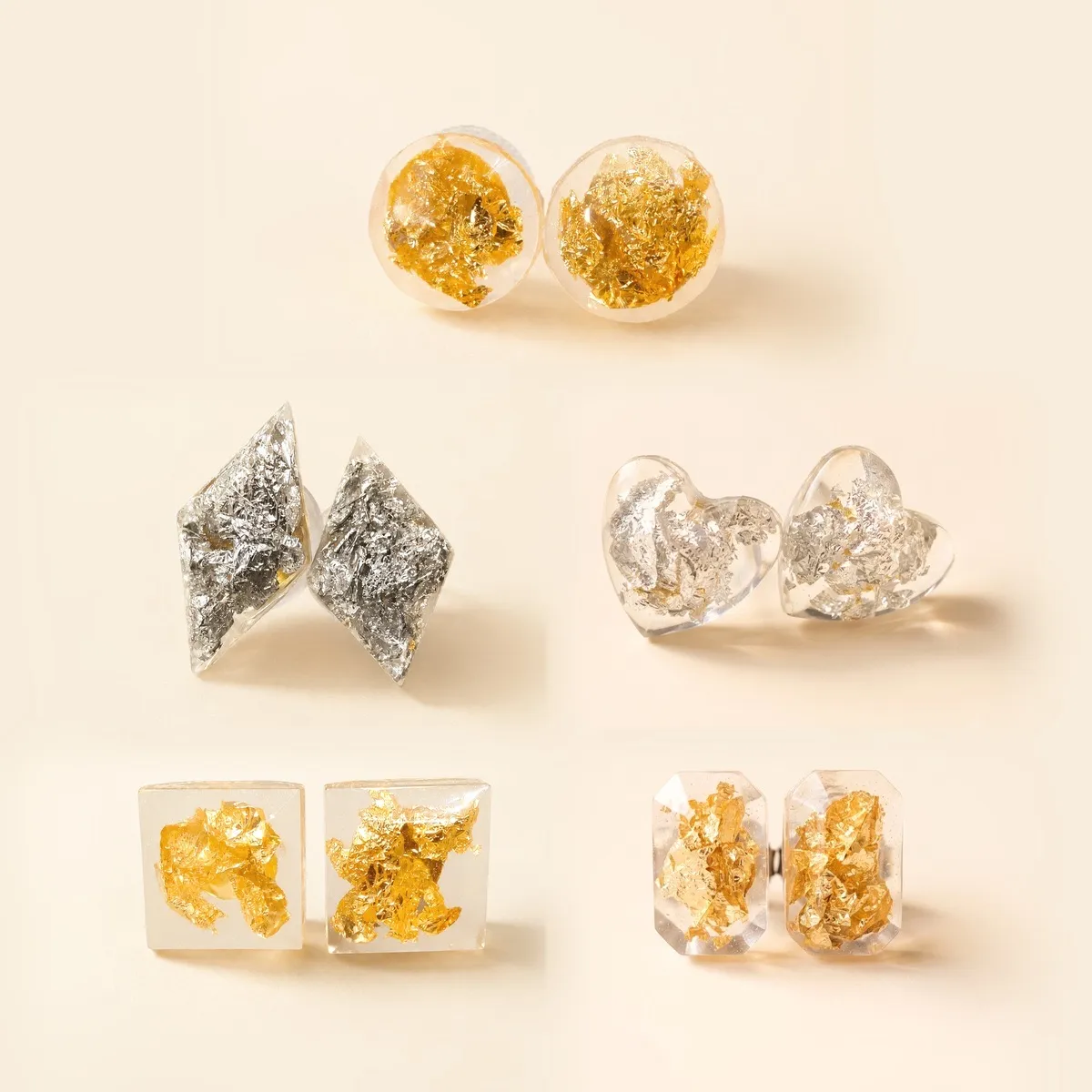Five pairs of clear resin studs in square, kite, round, heart and rectangle shapes, set with gold and silver foil flake