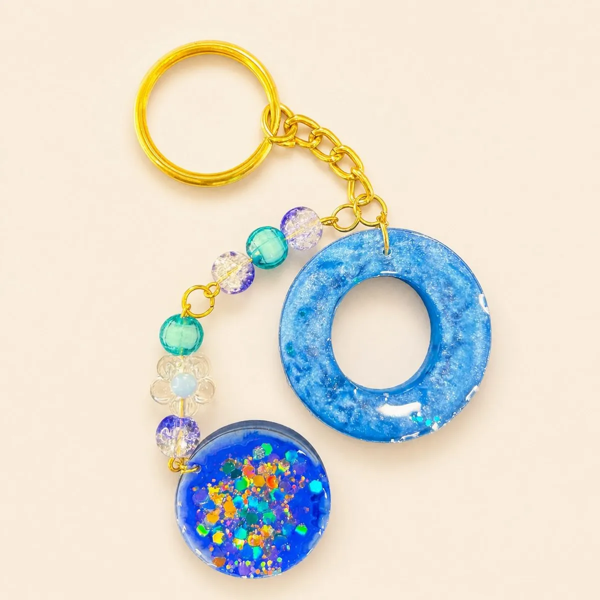 Blue glittery donut charm beside a clear disc packed with holographic confetti