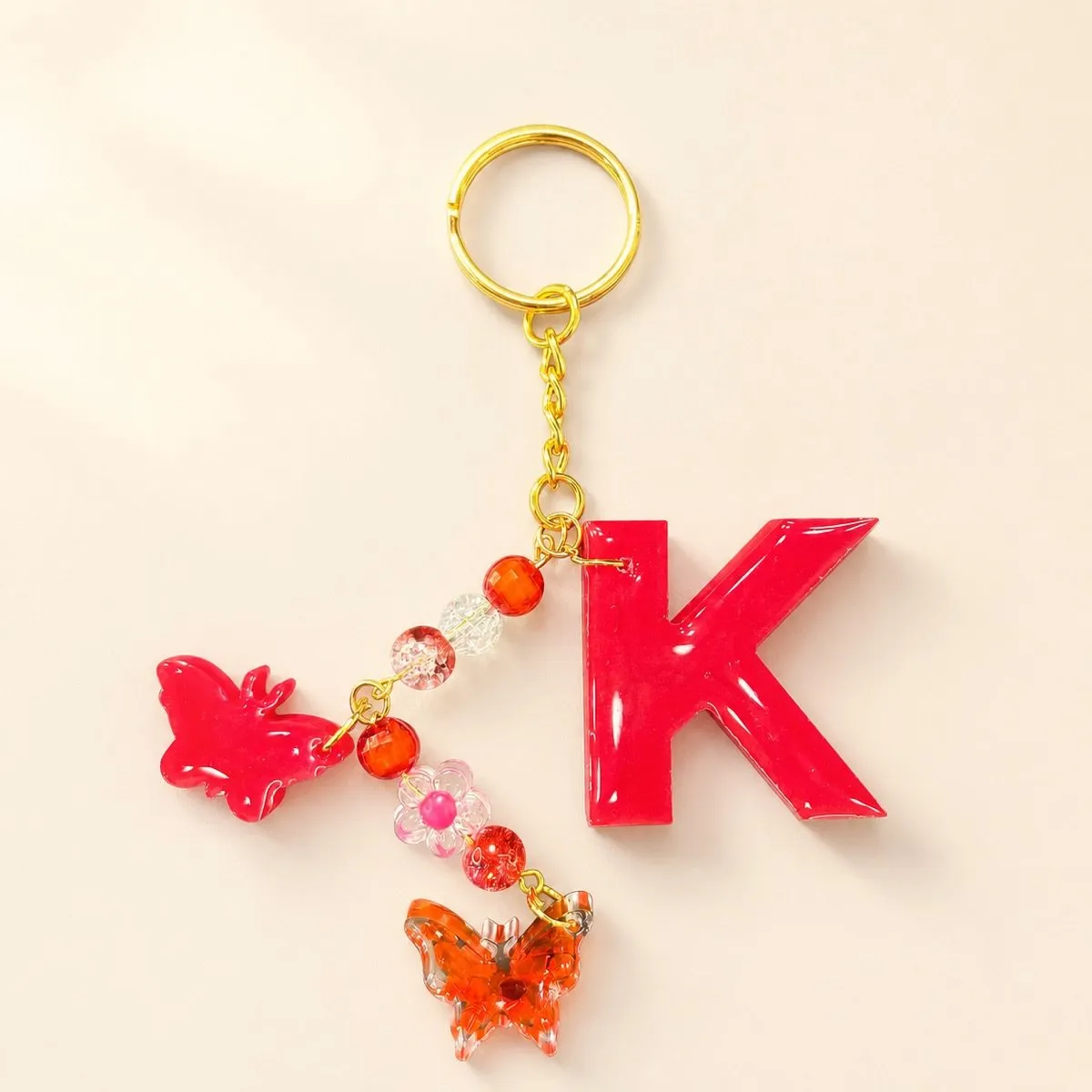 Glossy crimson letter K keychain with red and clear crackle beads and a butterfly charm