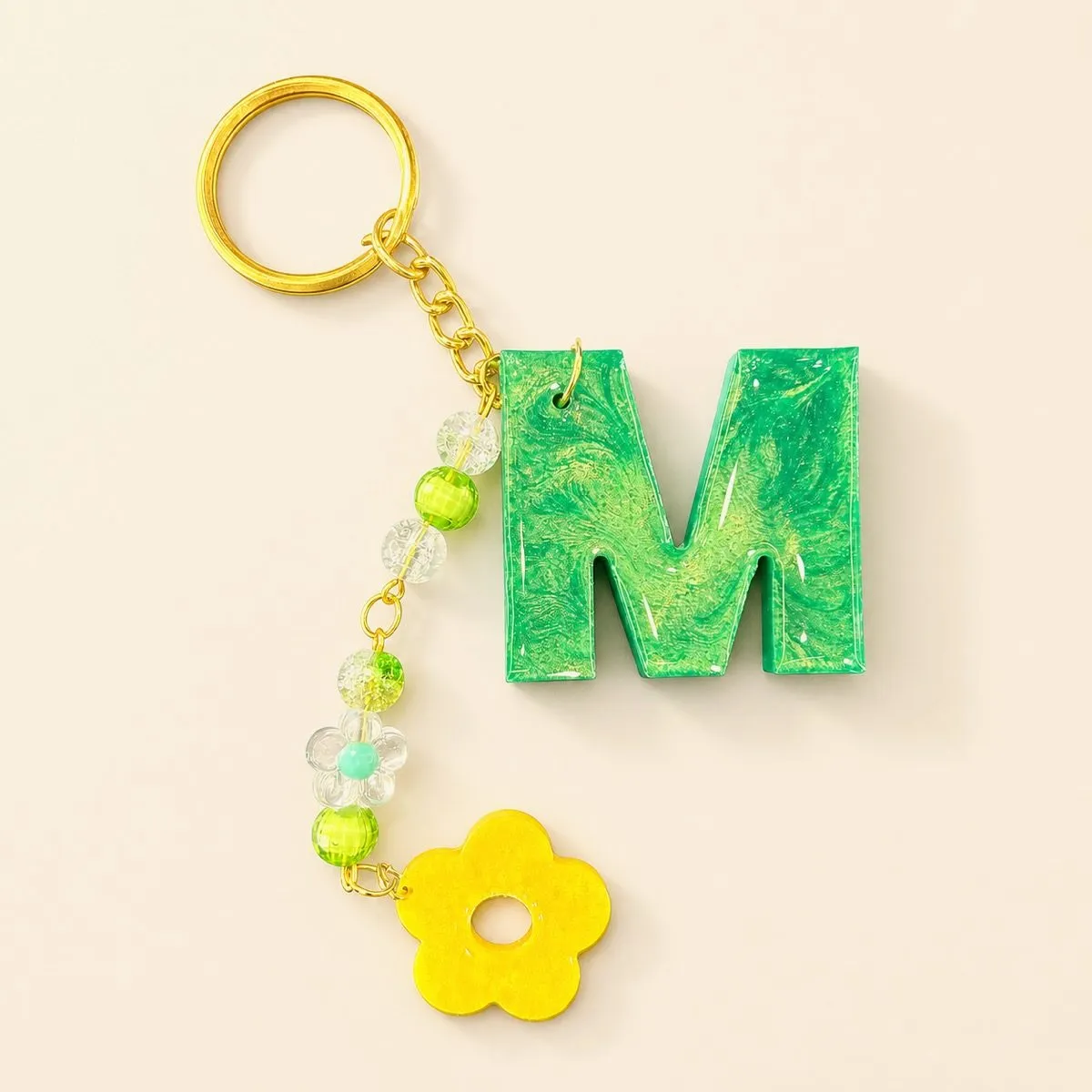 Green marbled letter M keychain with gold swirls and a yellow flower charm