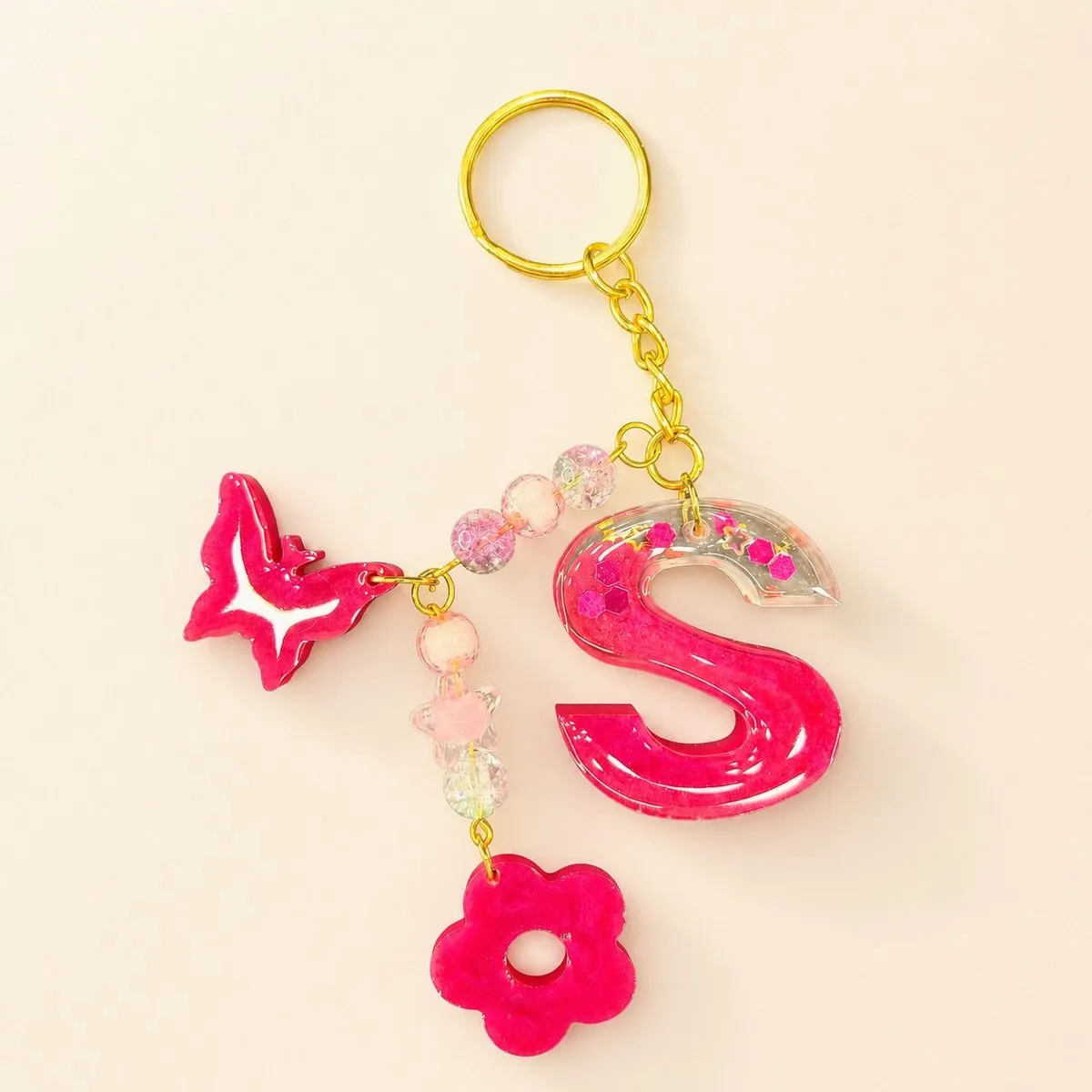 Hot pink glossy letter S keychain with pink crackle beads, a butterfly charm and a flower charm