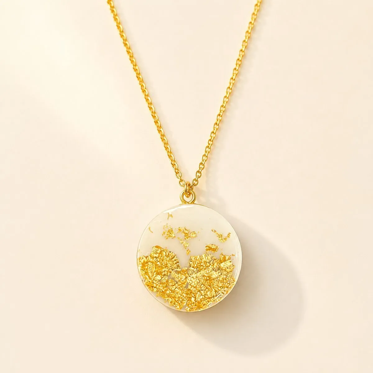 Fine gold chain with a round white pendant, gold leaf flake gathered low